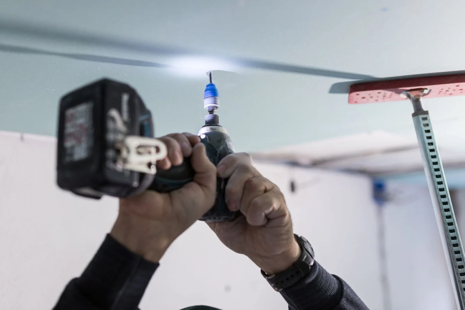 Plasterer fixing a ceiling with a drill