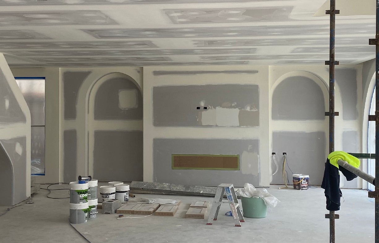 Plasterer finishing a freshly set plasterboard wall